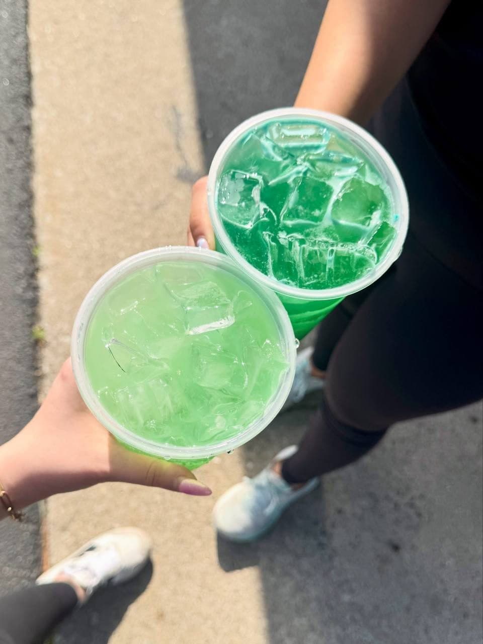 Two green loaded teas held together in a cheers outside the club