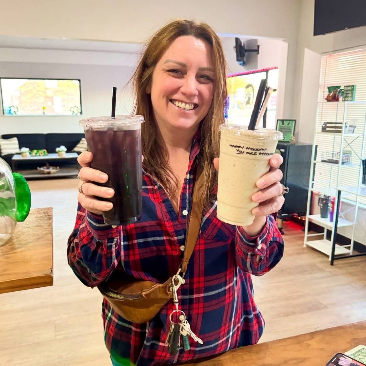 A smiling guest holding a dark loaded tea and a shake with a hand-written Happy Monday note